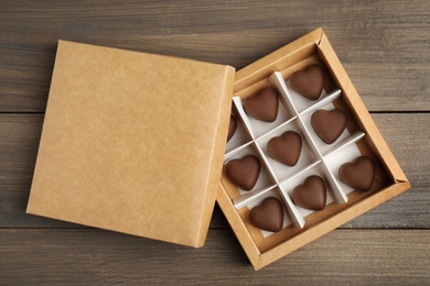 Photo of Tasty heart shaped chocolate candies on wooden table, flat lay. Happy Valentine's day