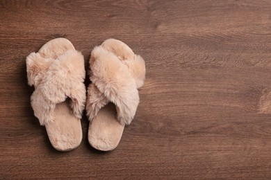 Pair of soft slippers on wooden floor, top view. Space for text