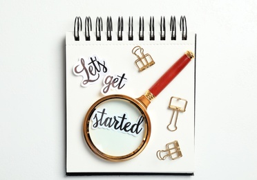 Sheets of paper with phrase Let's Get Started, stationery and magnifying glass on white table, top view
