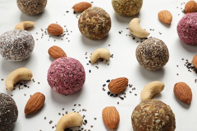 Photo of Delicious vegan candy balls and nuts on white table