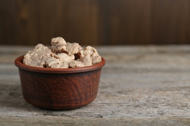Photo of Bowl of tasty cod liver on wooden table, closeup. Space for text