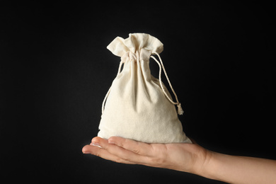 Woman holding full cotton eco bag on black background, closeup