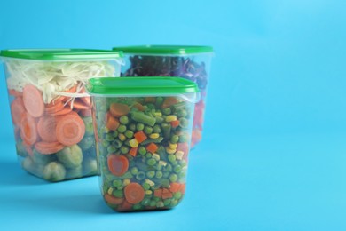Set of plastic containers with fresh food on light blue background, space for text
