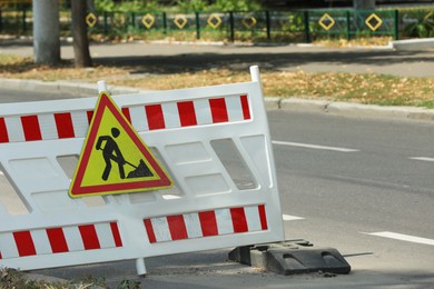 Photo of Barricade with road construction sign on city street. Repair works