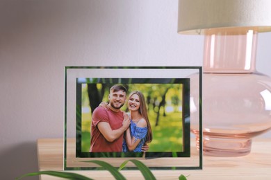 Frame with photo of young couple on wooden table indoors