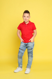 Full length portrait of cute little boy on yellow background