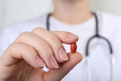 Doctor holding red pill, closeup. Anemia concept