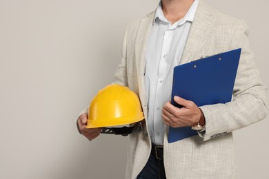 Photo of Professional engineer with hard hat and clipboard on white background, closeup