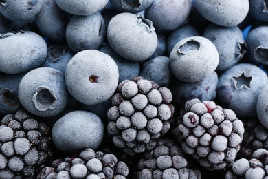 Tasty frozen blackberries and blueberries as background, top view