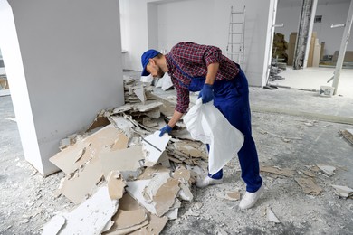Photo of Construction worker with used building materials in room prepared for renovation