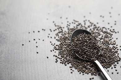 Photo of Spoon with chia seeds on grey table, space for text