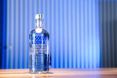 Photo of MYKOLAIV, UKRAINE - SEPTEMBER 23, 2019: Bottle of Absolut vodka on wooden bar counter. Space for text