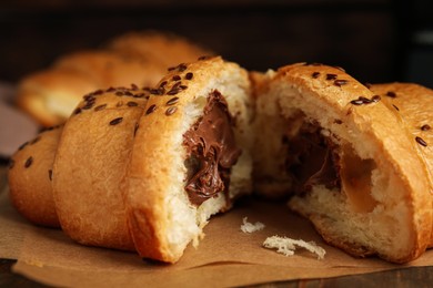 Tasty croissant with chocolate and sesame seeds on parchment, closeup