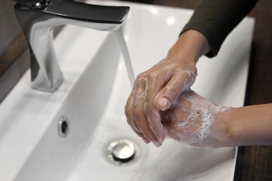 Woman washing hands in sink, closeup view