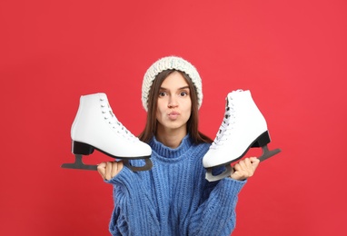 Pretty woman with ice skates on red background