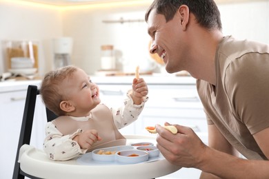 Father feeding his cute little baby healthy food at home