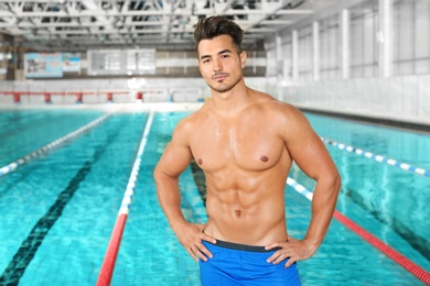 Young athletic man near swimming pool indoors