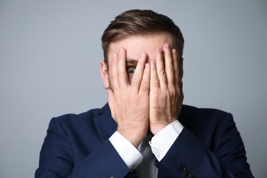 Photo of Young businessman feeling fear on grey background