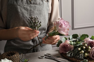 Florist creating beautiful bouquet at grey table, closeup