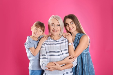 Beautiful mature woman with daughter and grandchild on color background