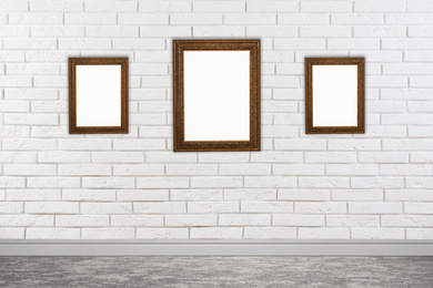 Frames with empty canvases on brick wall in modern art gallery. Space for design