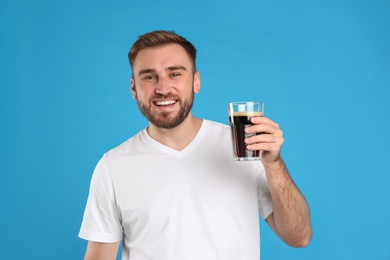 Handsome man with cold kvass on blue background. Traditional Russian summer drink