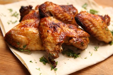 Photo of Delicious grilled chicken wings with pita bread served on wooden table, closeup
