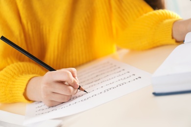 Child writing music notes at table, closeup