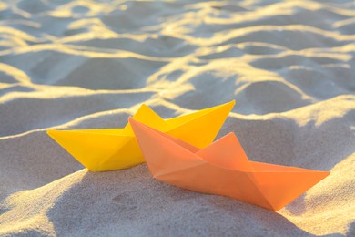 Photo of Two colorful paper boats on sand outdoors