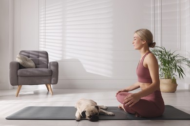 Beautiful woman with dog practicing yoga at home