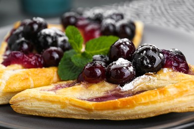 Photo of Fresh tasty puff pastry with sugar powder, jam, sweet berries and mint, closeup