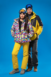 Couple wearing stylish winter sport clothes on light blue background