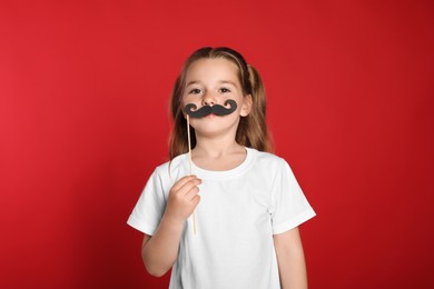 Photo of Little girl with fake mustache on red background