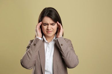 Young woman suffering from migraine on beige background