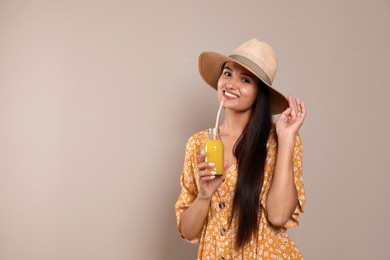 Beautiful young woman with straw hat and glass of refreshing drink on beige background. Space for text