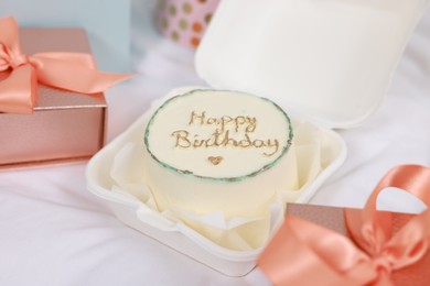 Photo of Delicious decorated cake and gifts on white cloth. Happy Birthday