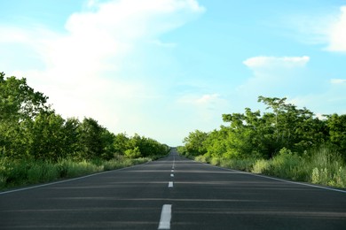 Asphalt road running through countryside on sunny day
