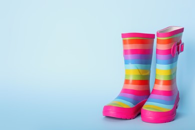 Pair of striped rubber boots on light blue background. Space for text