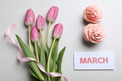 8 March greeting card design with tulips and cupcakes on light grey background, flat lay. International Women's day