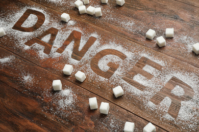 Photo of Composition with word DANGER and sugar on wooden table