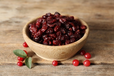 Photo of Dried and fresh cranberries on wooden table