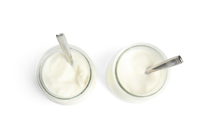 Tasty organic yogurt in glass jars with spoons isolated on white, top view