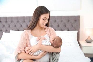 Young woman with her newborn baby in bedroom