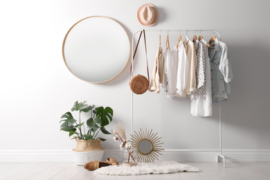 Rack with stylish women's clothes and mirror indoors. Interior design