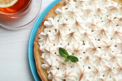 Delicious lemon meringue pie decorated with mint on white wooden table, flat lay