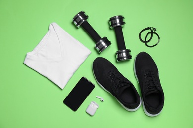 Sportswear and equipment on green background, flat lay