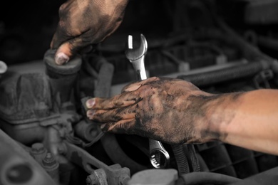 Photo of Dirty mechanic fixing car, closeup of hands