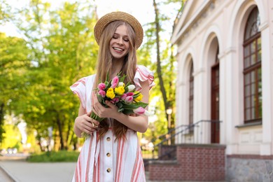 Beautiful teenage girl with bouquet of tulips on city street