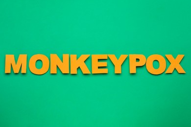 Photo of Word Monkeypox made of bright letters on green background, top view
