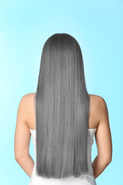 Woman with gray hair on light blue background, back view